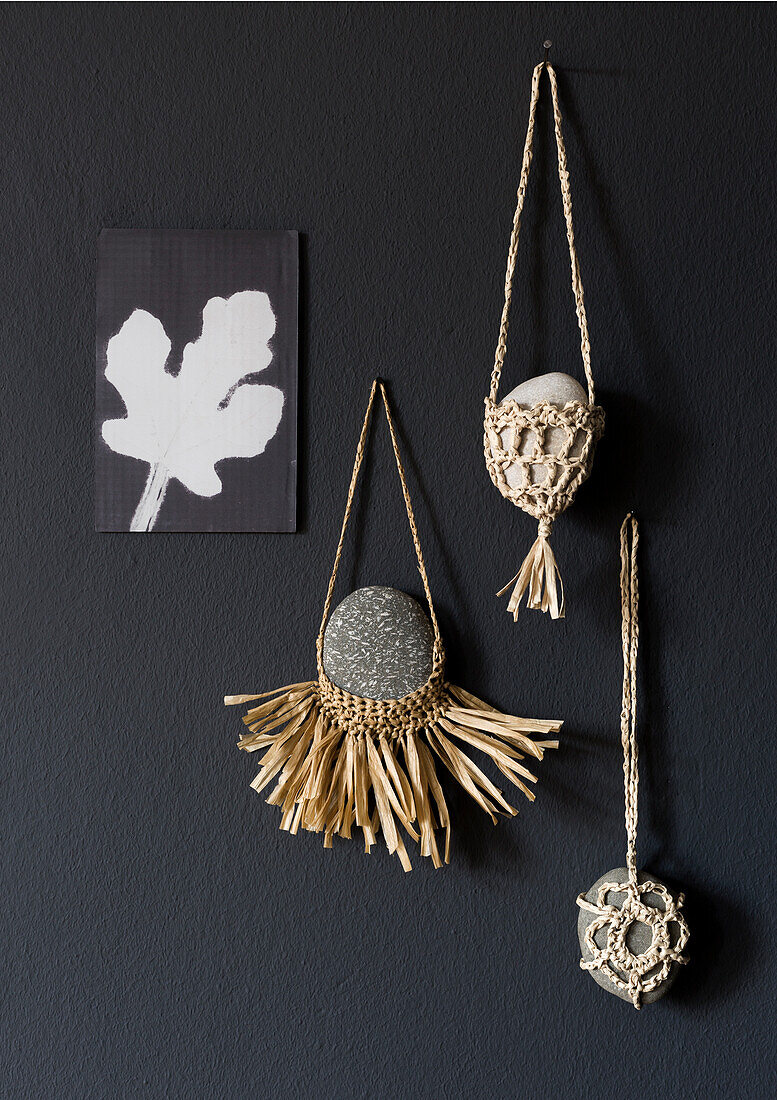 Macramé wall decoration with stones and plant motif picture on dark grey wall