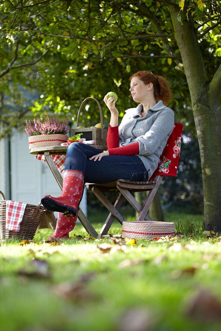 Frau sitzend im Obstgarten