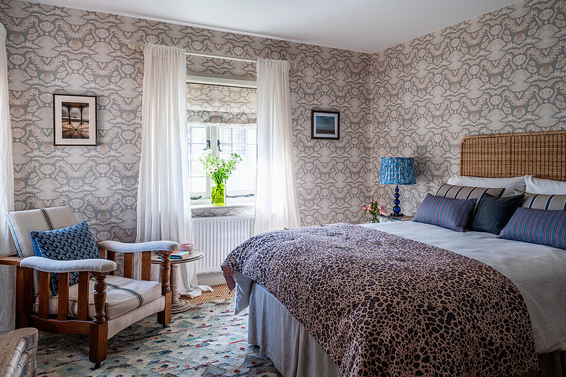 Bedroom with patterned wallpaper and double bed with leopard print blanket