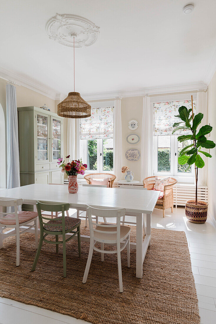 Dining room with white furniture, rattan armchairs and floral fabric blinds