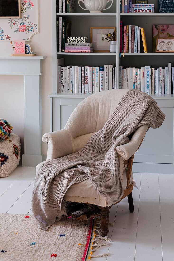 Reading chair with beige blanket in front of pastel blue bookshelf in the living room