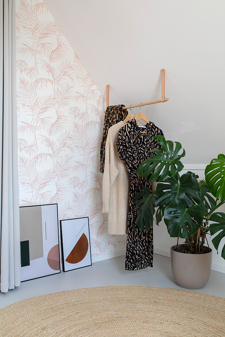 Corner in the bedroom with plants, clothes and minimalist art