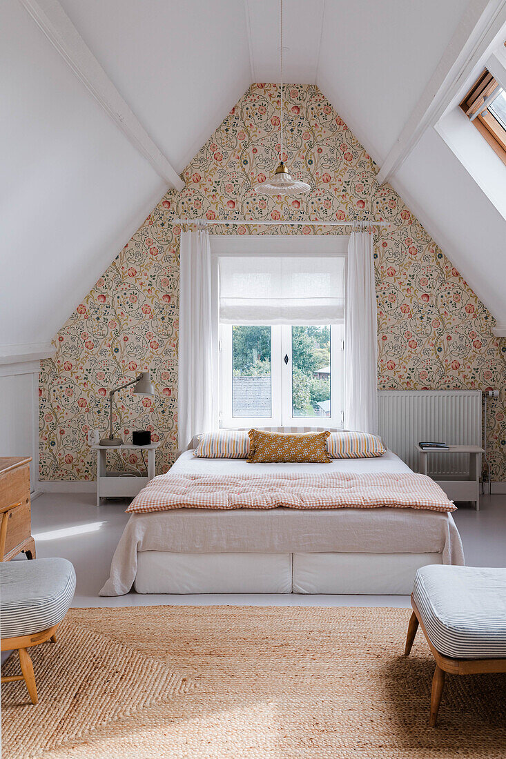 Attic bedroom with floral wallpaper, sisal carpet and skylight