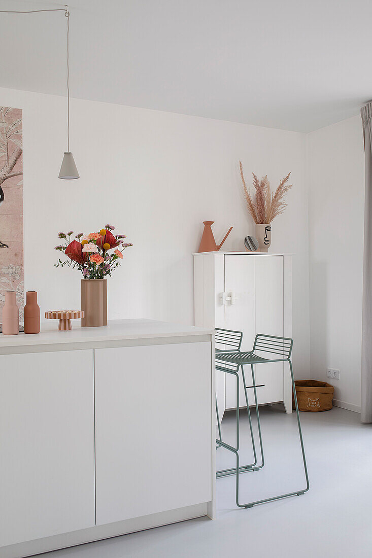 White kitchen with minimalist bar stools and dried flower decoration