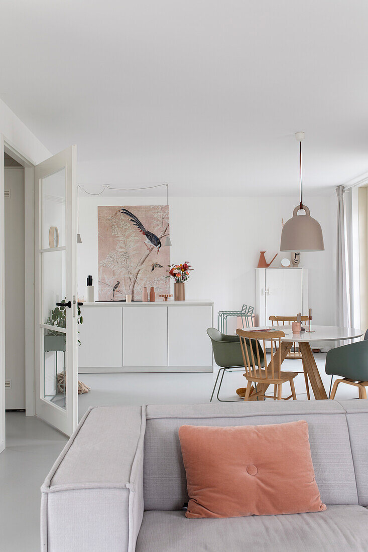 Open-plan living and dining area with white furnishings and pastel-coloured accents