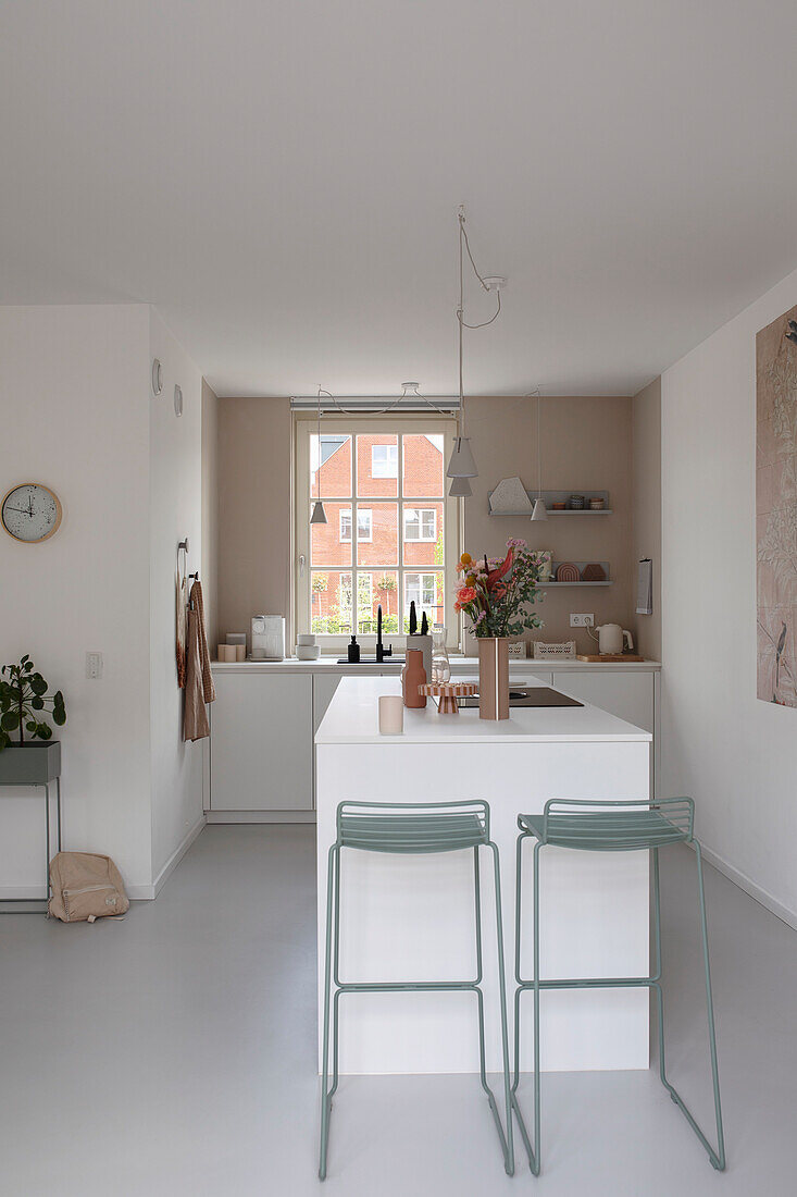 Modern, white kitchen with island and sage green bar stools