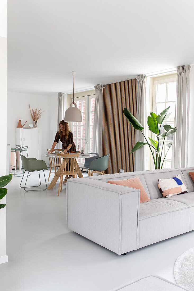 Open-plan living area with grey sofa, wooden dining table and wall panels