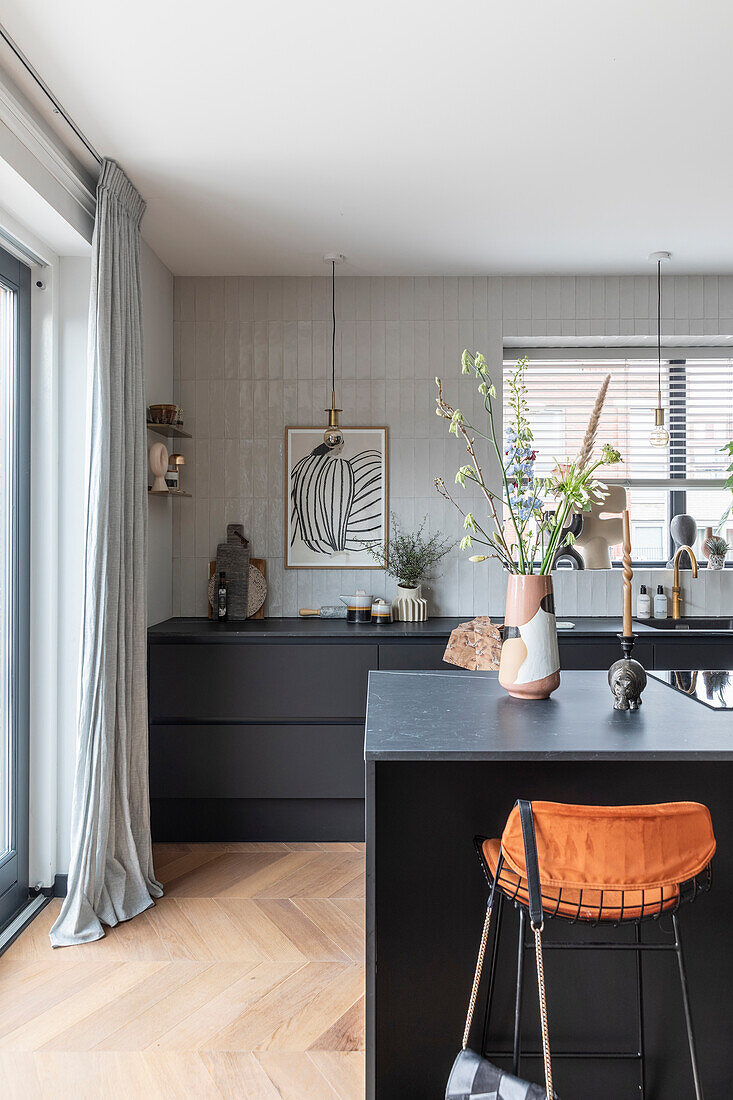 Modern kitchen with black base units and orange bar stool