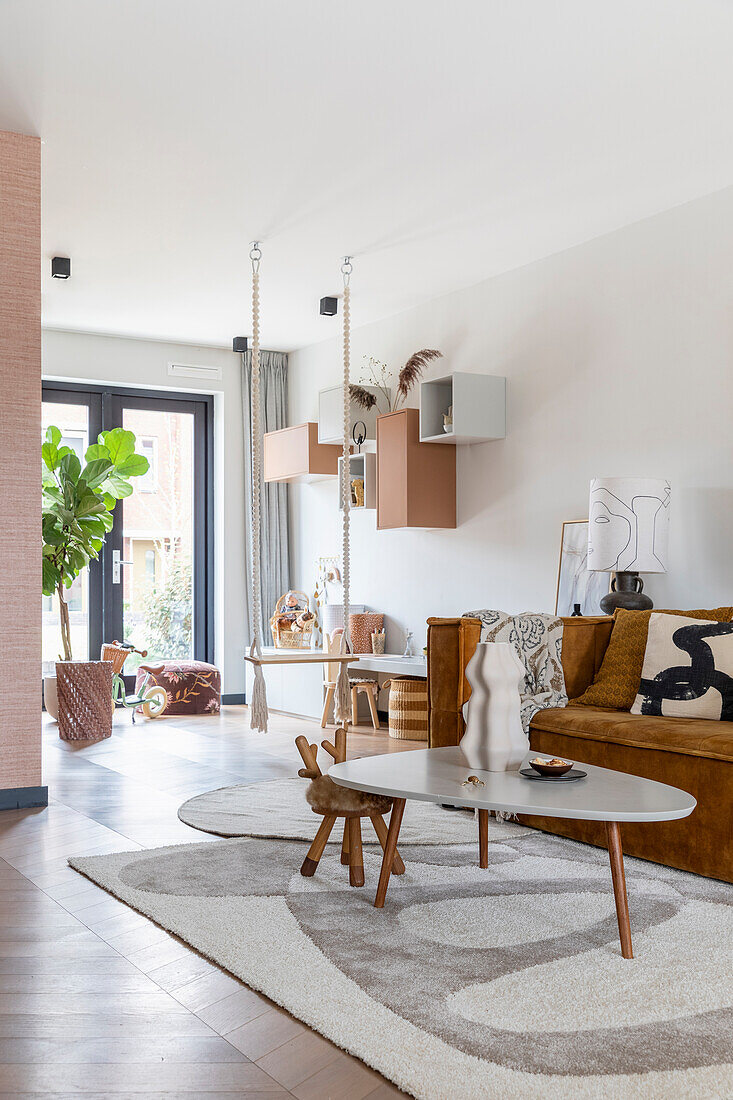 Modern living room with brown sofa, hanging shelves and large rug in earthy tones