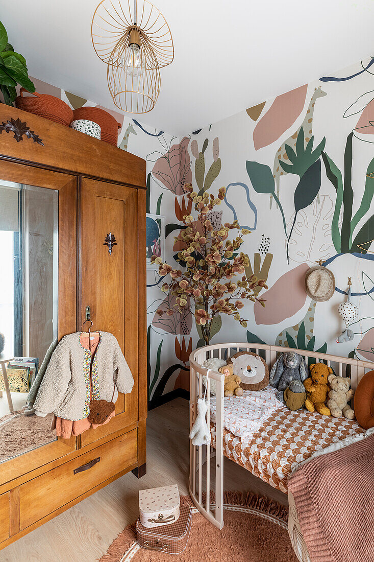 Buntes Kinderzimmer mit Holzschrank, Gitterbett und Wanddekor im botanischen Stil