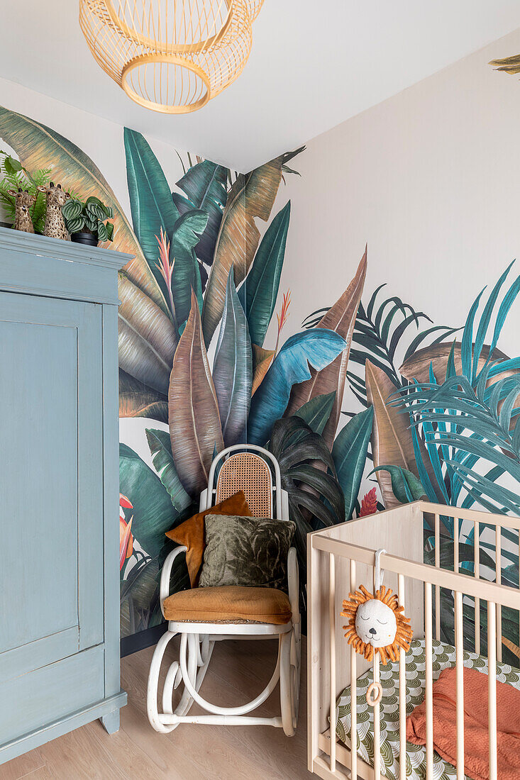 Baby room with exotic jungle wallpaper, cot and rocking chair