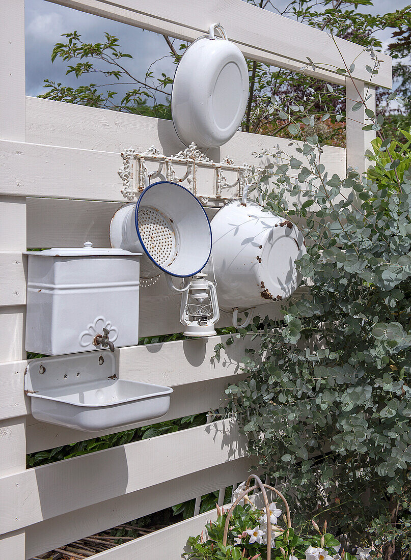 Decorative, white kitchen utensils on wooden wall in garden next to eucalyptus plant