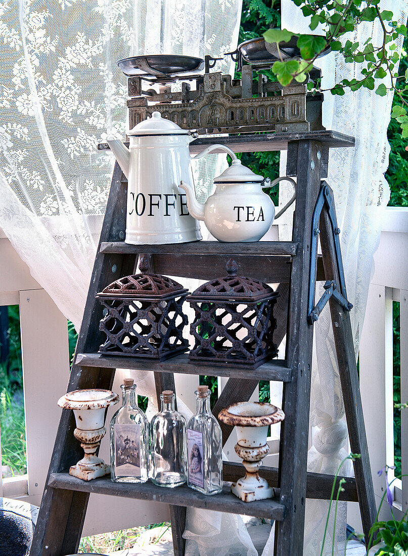 Decorative ladder with vintage teapots, metal lanterns and glass bottles