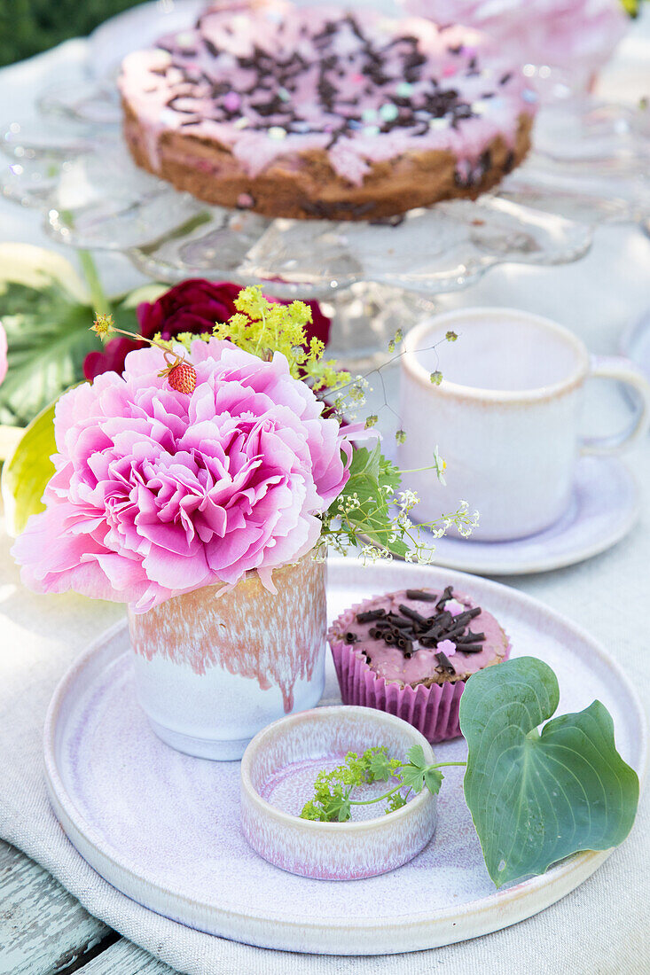 Kaffeetisch mit rosa Blütendekoration und Gebäck