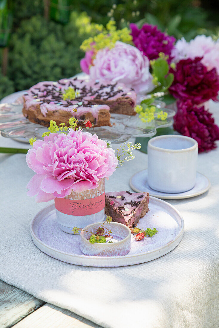 Pink peonies (Paeonia) next to chocolate cake in the garden