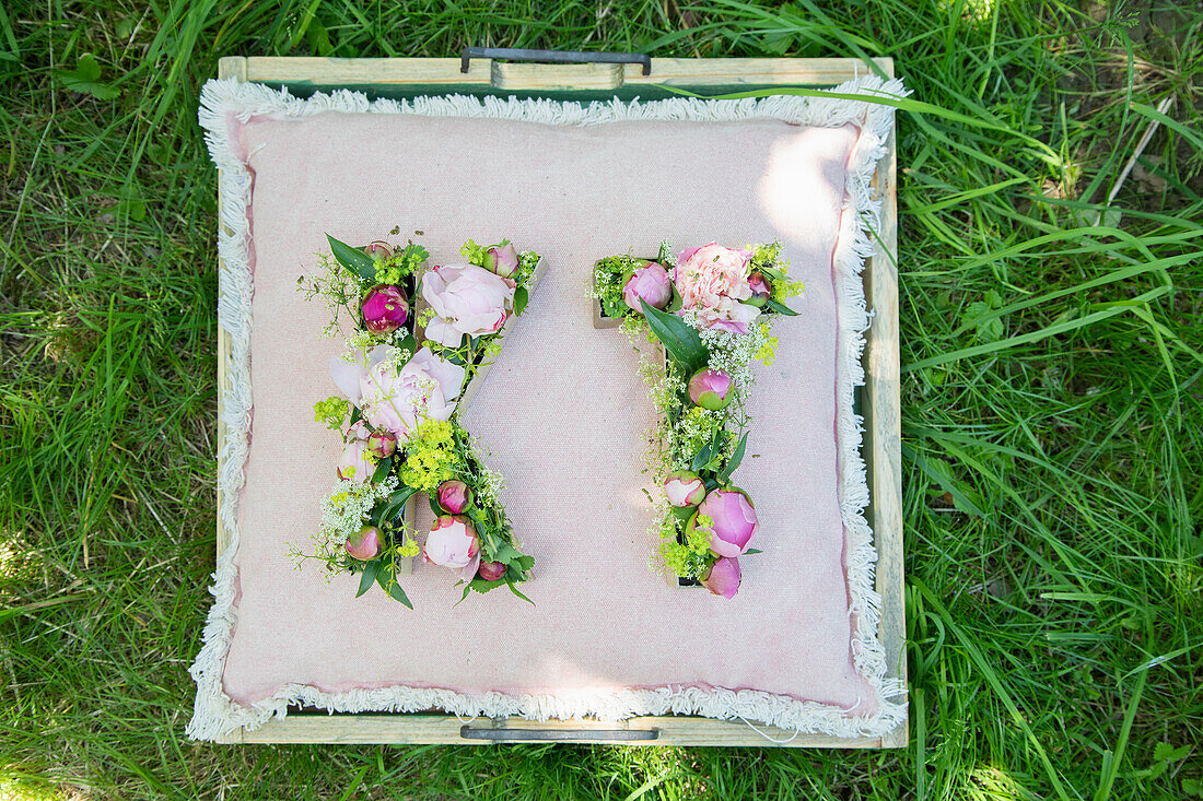 Cushion with letter-shaped flower arrangement on lawn