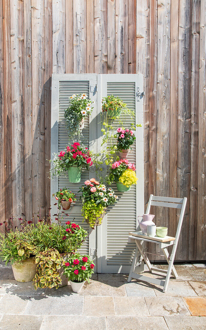 Dekorativer Fensterladen mit Blumen in Töpfen