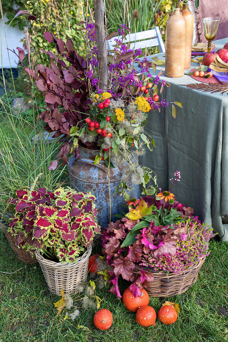 Herbstliche Dekoration mit Blumen und Früchten und gedecktem Tisch im Garten