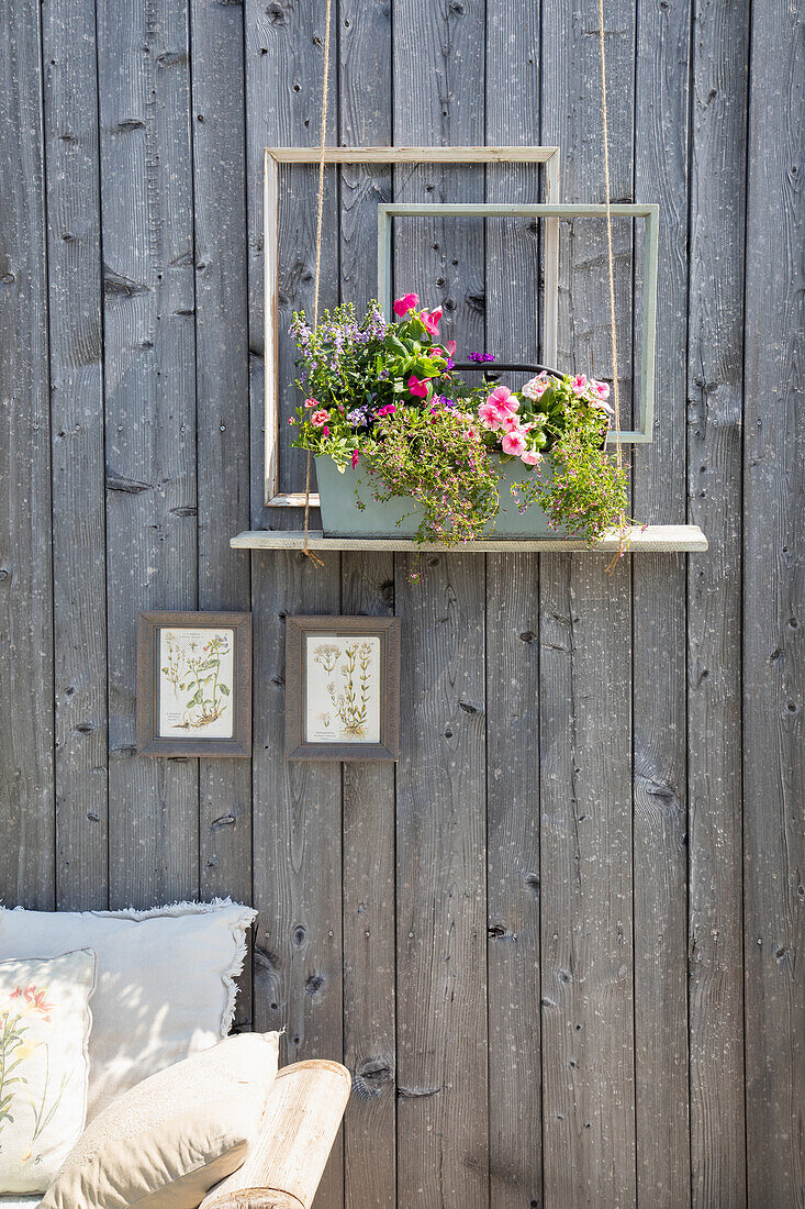 Decorative flower arrangement with empty picture frames in front of wooden wall in the garden