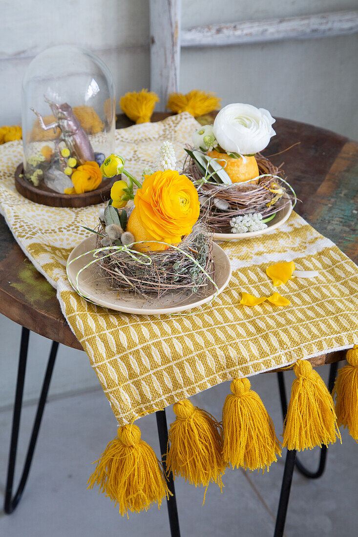 Osterdekoration mit gelben und weißen Ranunkeln (Ranunculus) auf Holztisch