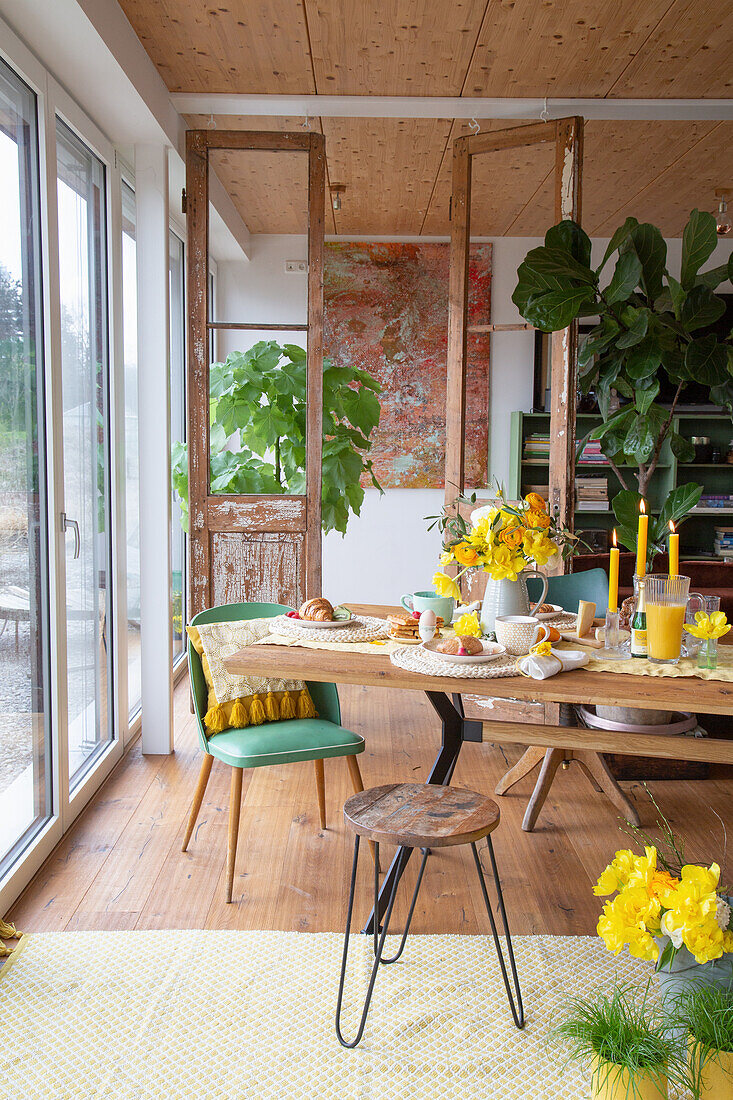 Dining area with wooden table, different chairs, yellow and green accents