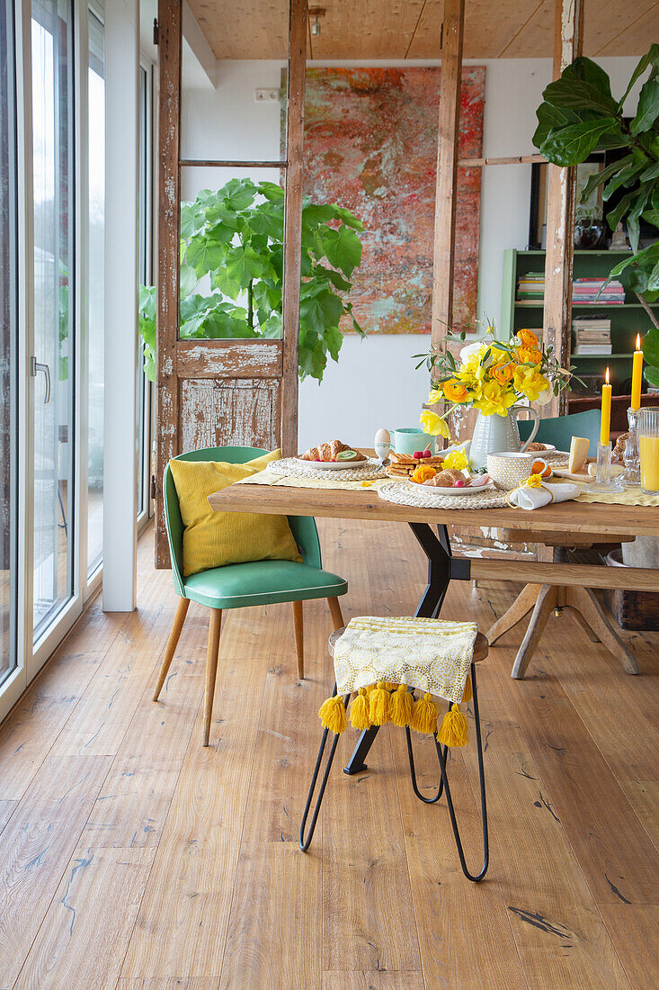 Dining area with wooden table, parquet floor and green and yellow accents