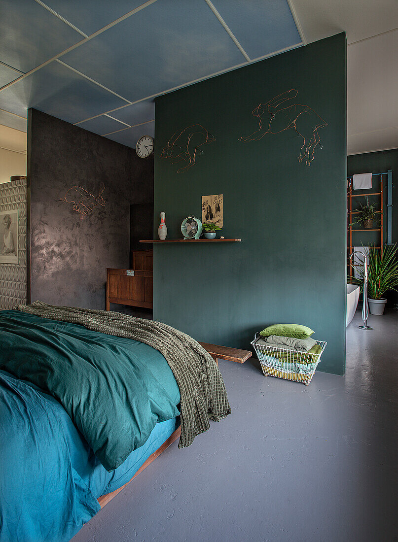 Bedroom with green and blue bed linen and green accent wall