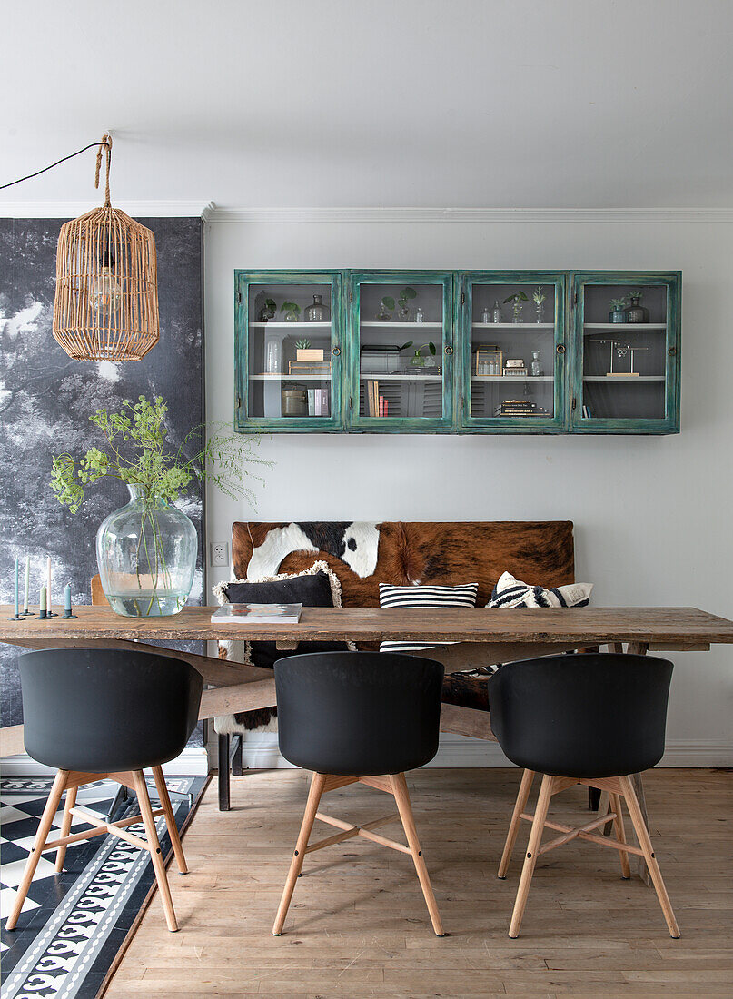 Dining area with rustic wooden table, modern chairs and green display cabinet