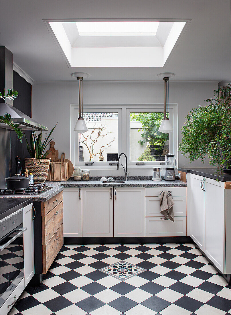 Bright kitchen with skylight, black and white chequerboard floor and wooden elements