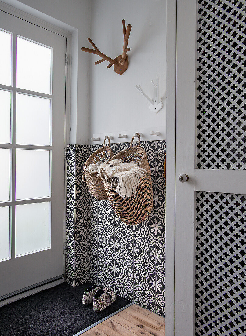 Narrow entrance area with patterned wall tiles, coat rack and basket accessories