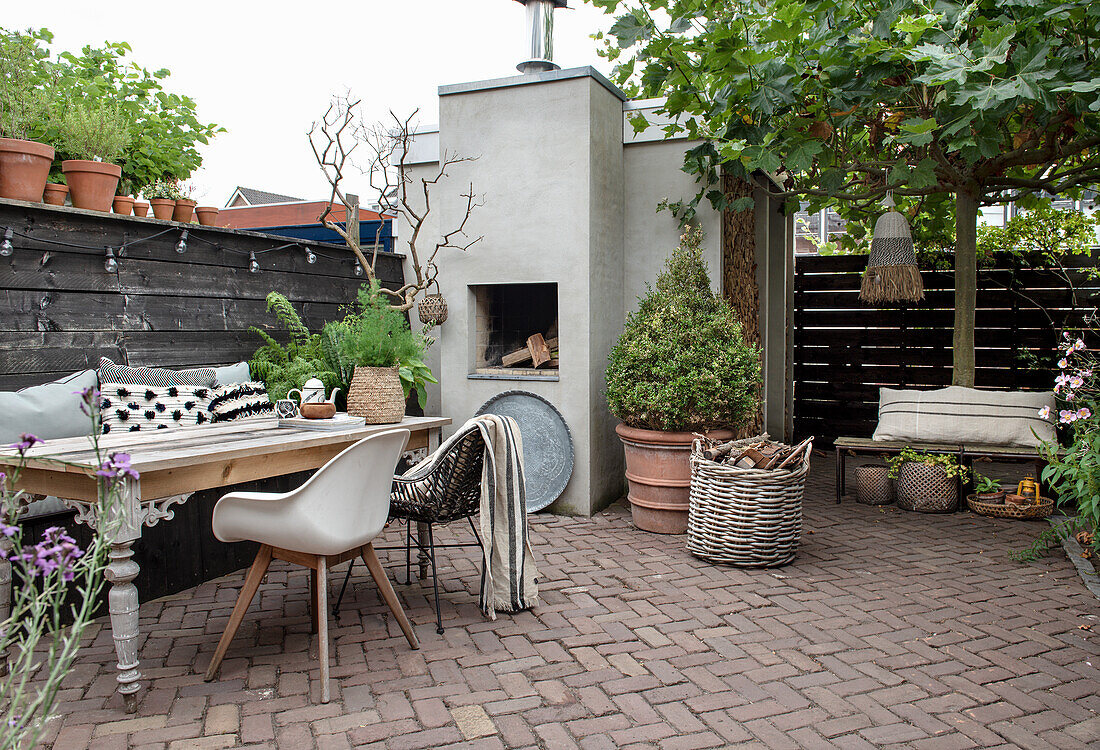 Cosy patio area with outdoor fireplace, wooden table and plants