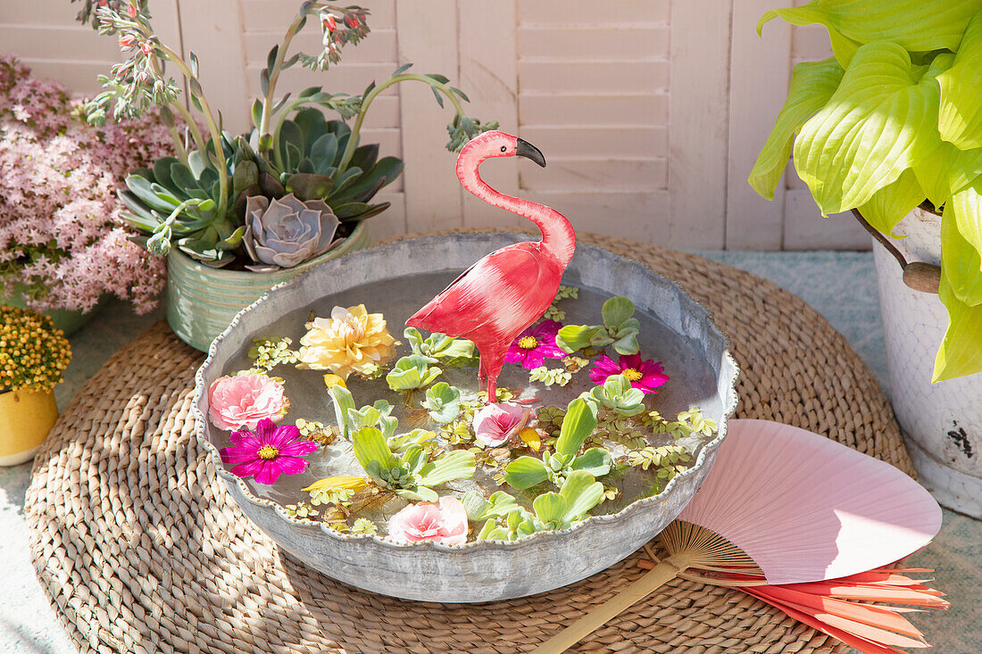 Mini pond in shallow pot with floating flowers and flamingo decoration outdoors