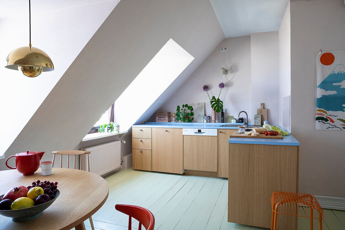 Bright kitchen in pastel colours with sloping roof and wooden furniture