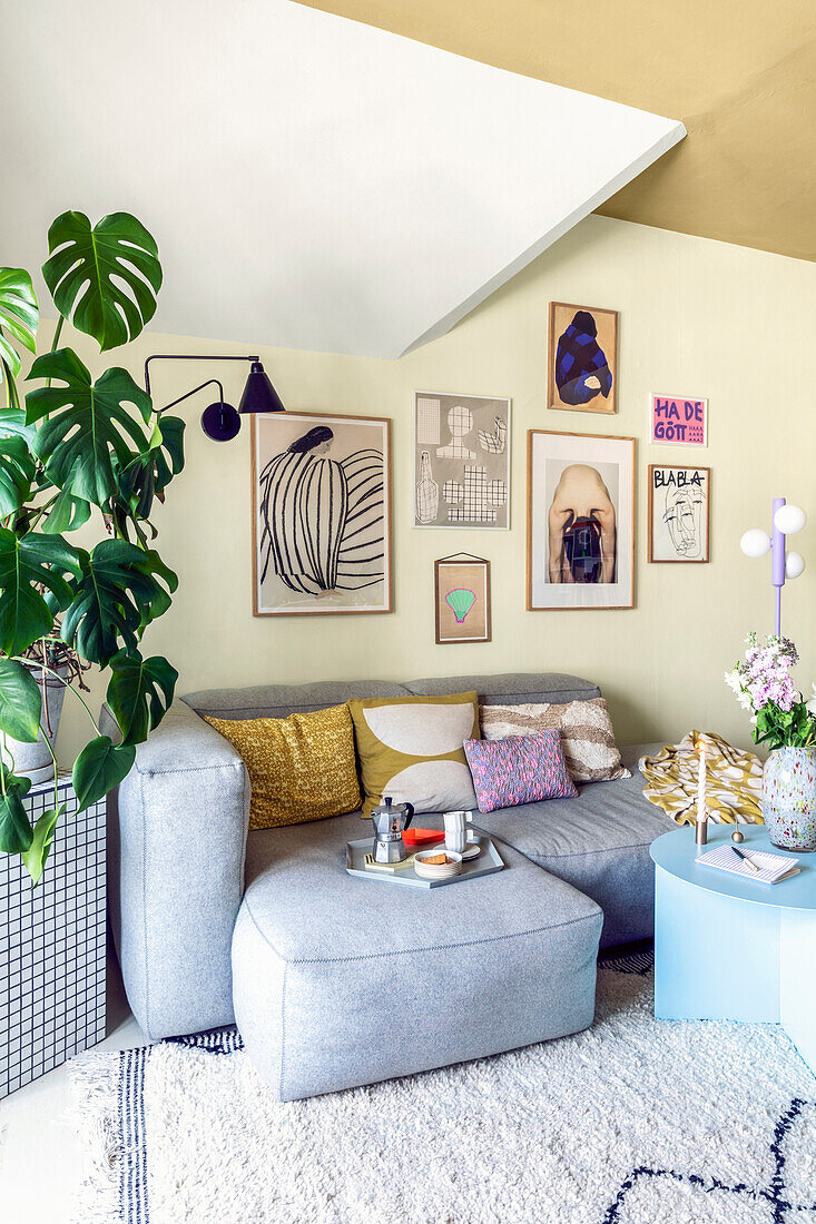 Corner of a living room with light grey sofa and colourful murals