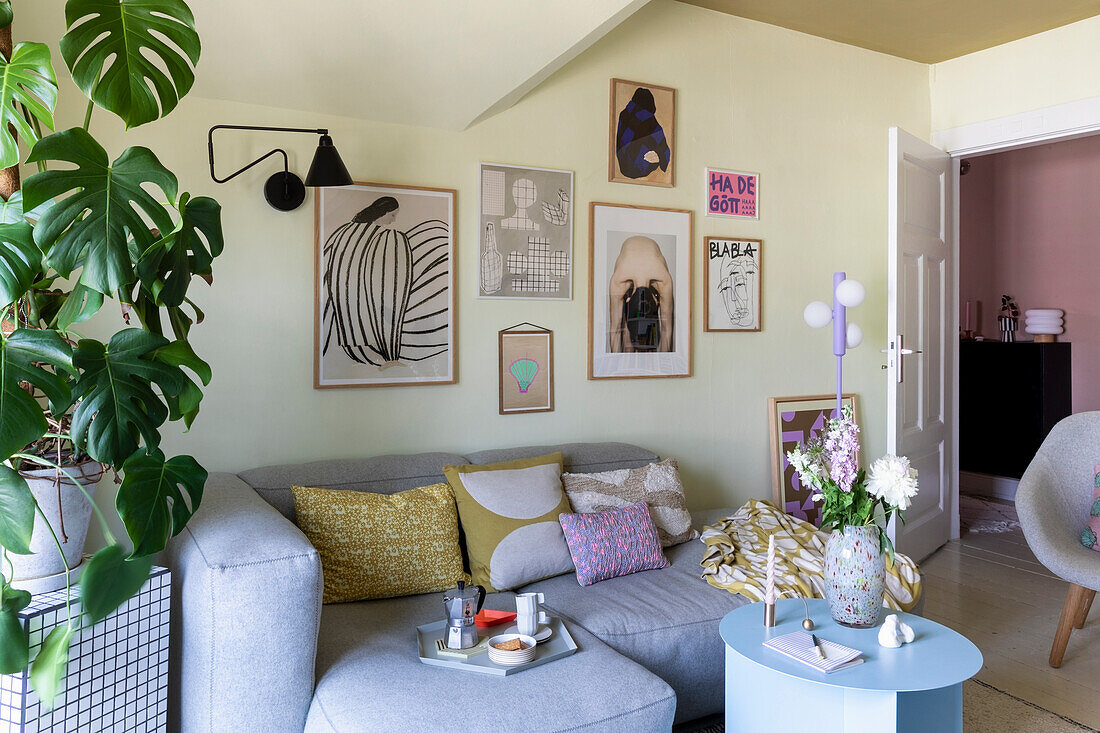 Modern living room corner with grey sofa, gallery wall and monstera plant