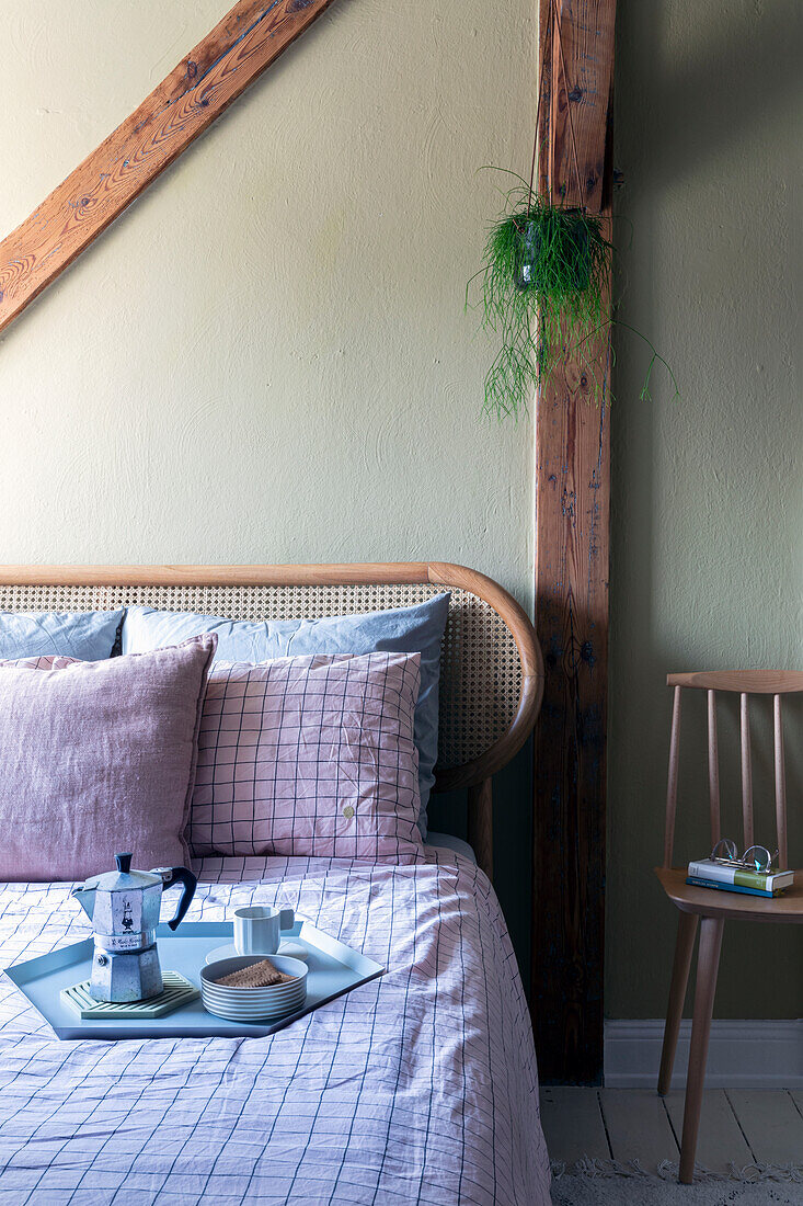 Schlafzimmer mit Rattanbett, rosa karierter Bettwäsche und Kaffeetablett