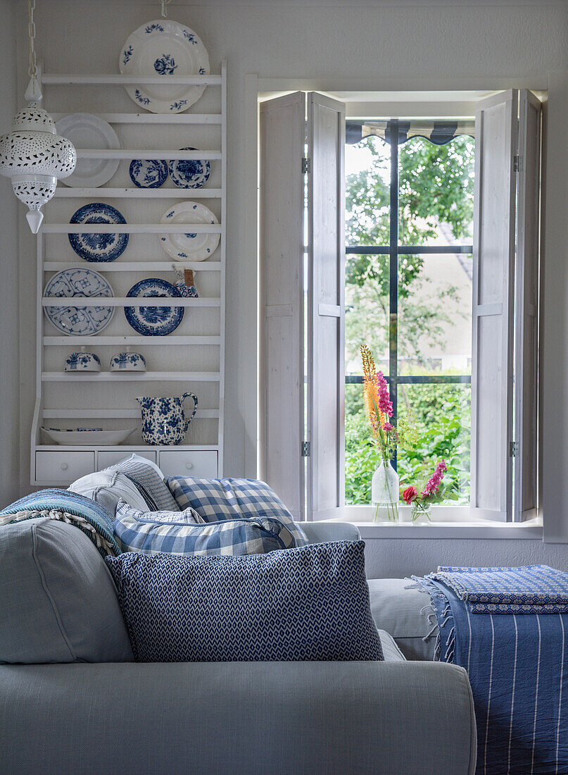 Living room with blue and white cushions and country-style plate rack