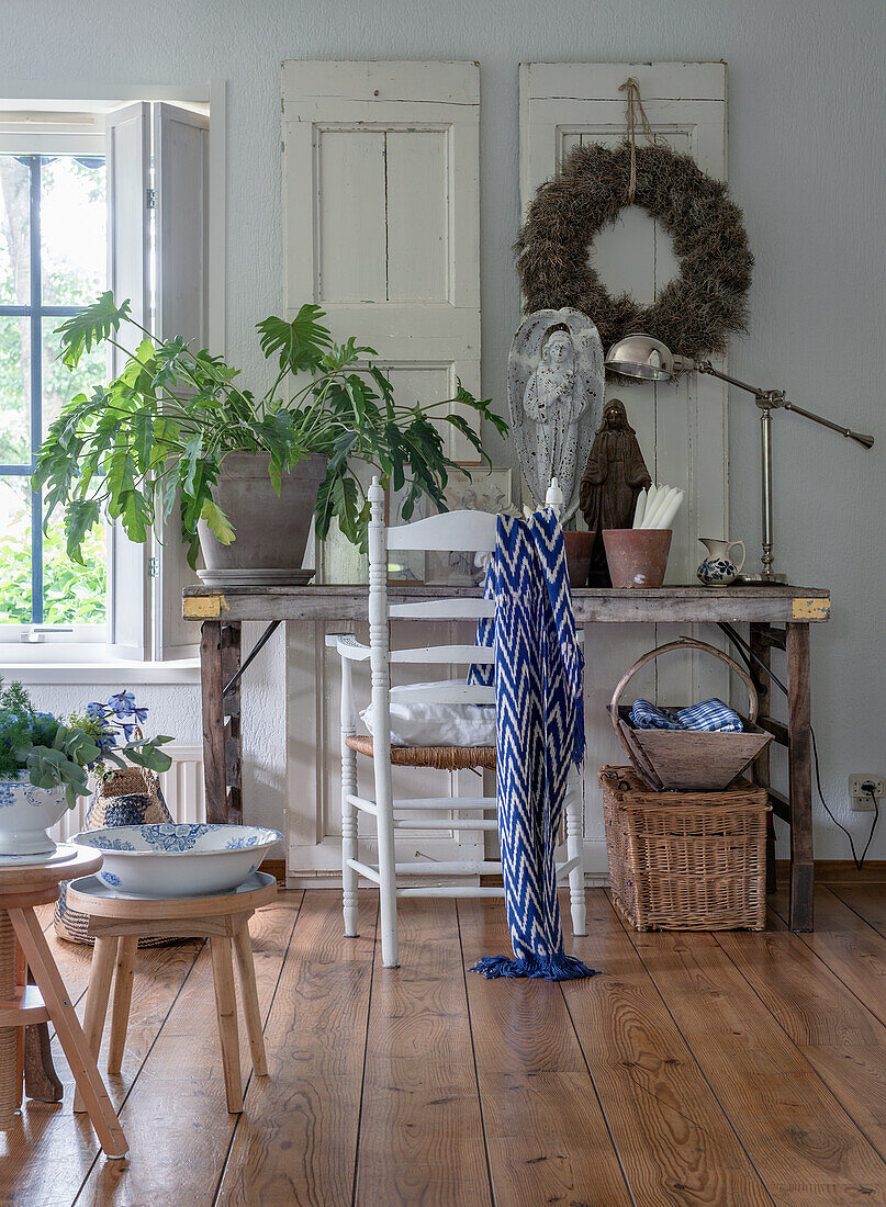 Country-style wooden table with plant, door wreath and table lamp