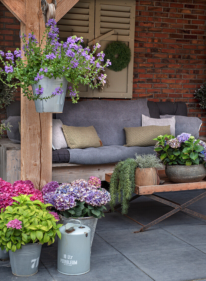 Sitzbereich auf Terrasse mit Blumen in Zinkkübeln