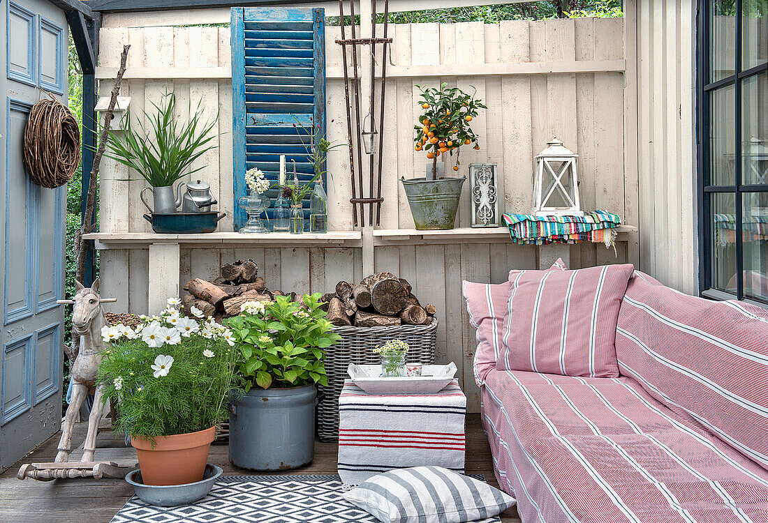 Terrasse mit gestreiftem Sofa, Topfpflanzen und rustikalen Holzelementen