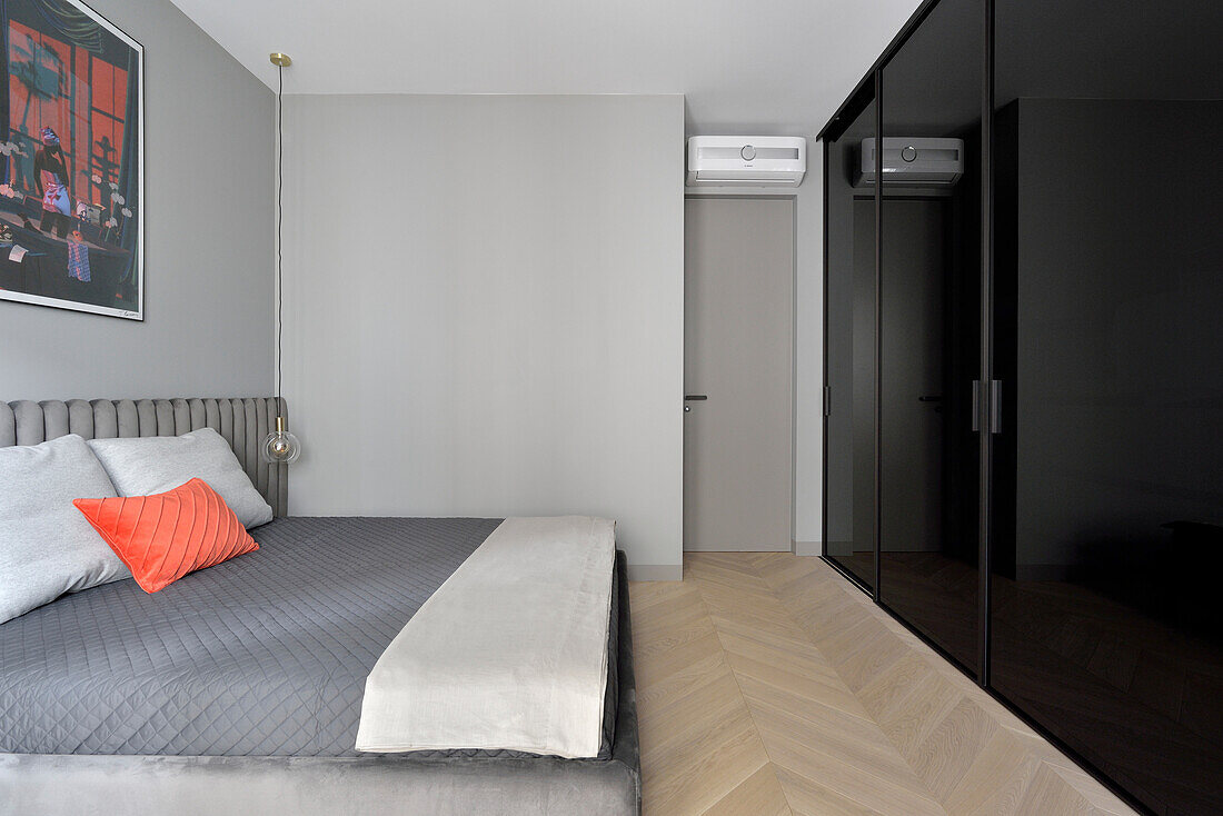 Schlafzimmer mit grauer Bettwäsche und Fischgrätparkett in Warschauer Wohnung