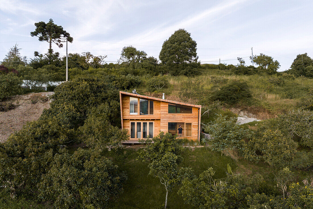 Modern wooden house on a hillside, surrounded by greenery, Ecuador 2023