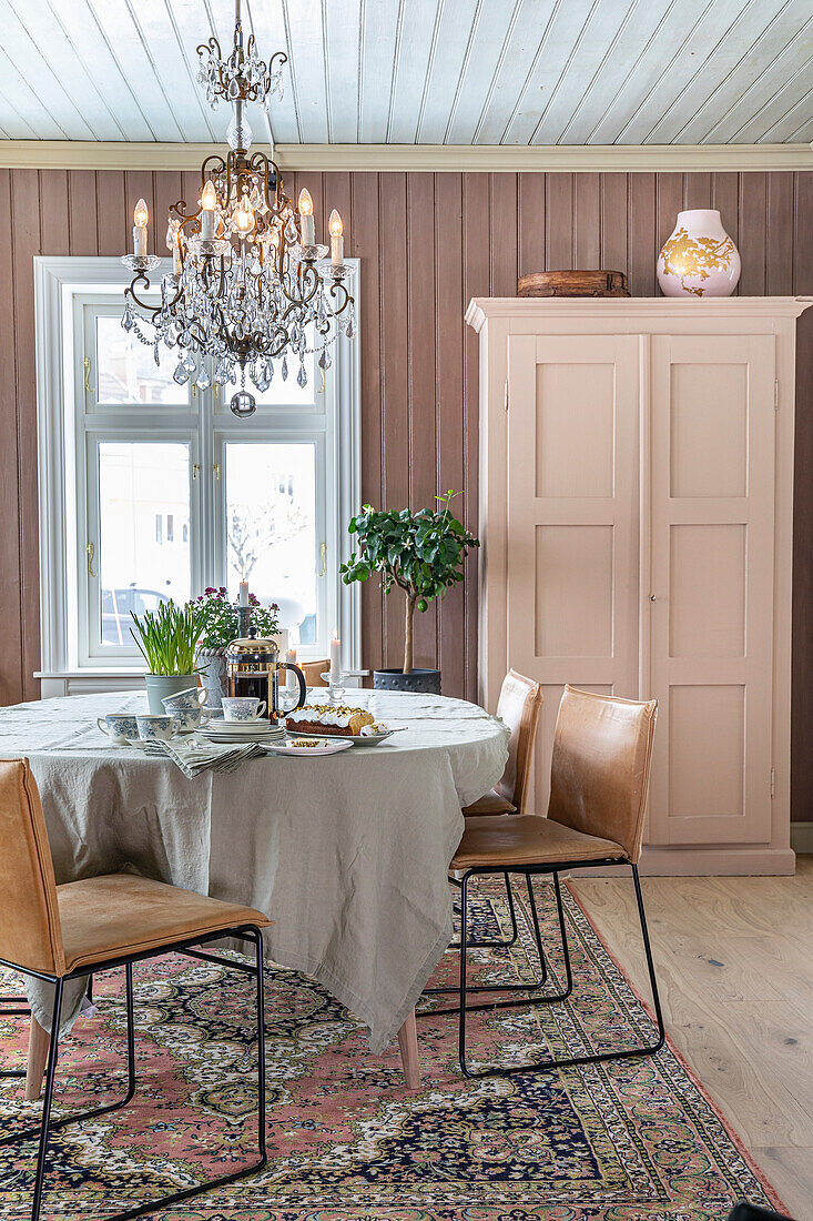 Dining room with chandelier, table with linen tablecloth and oriental rug