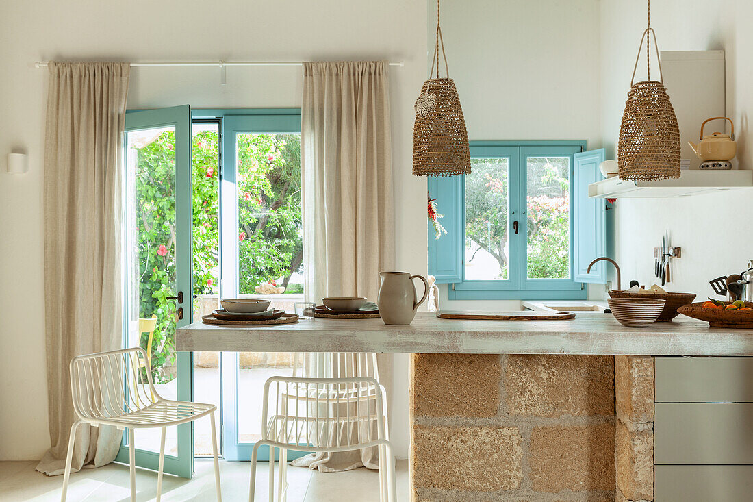 Bright kitchen with natural stone counter, blue window frames and view of the garden