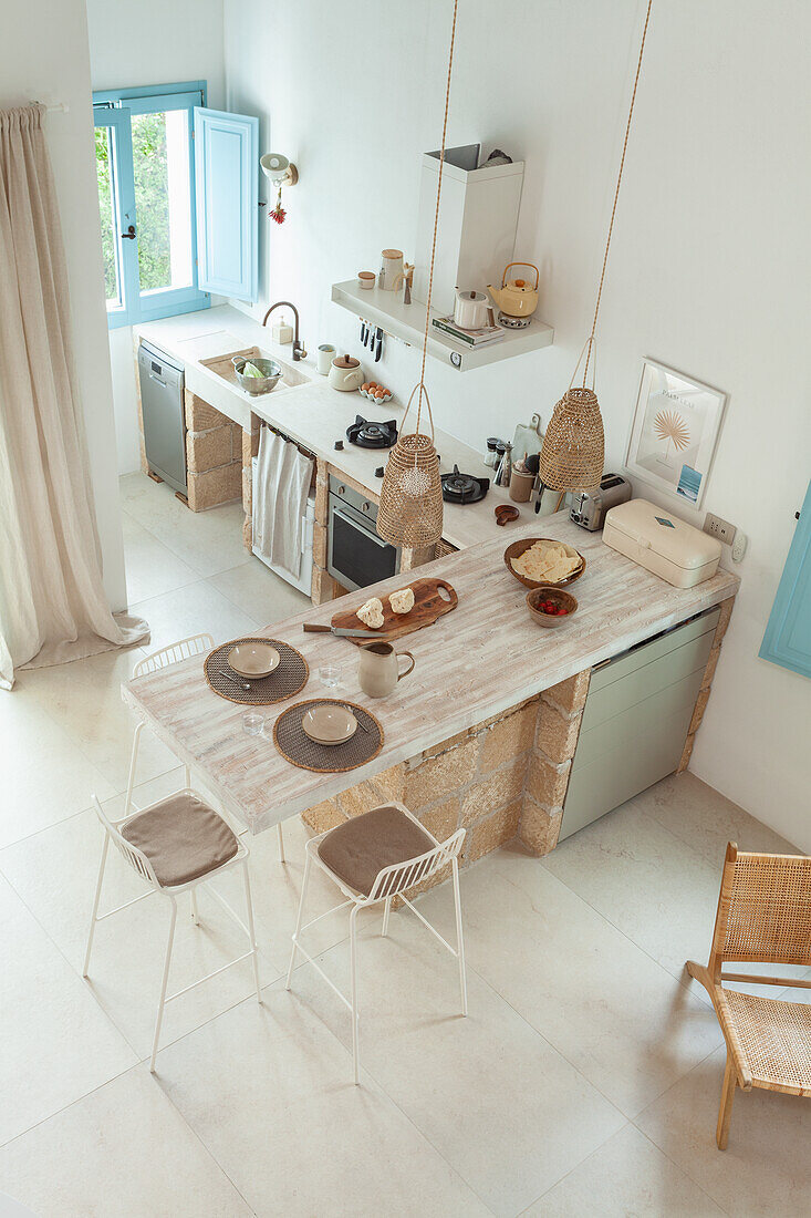 Bright kitchen with natural stone elements, breakfast bar and hanging lamps