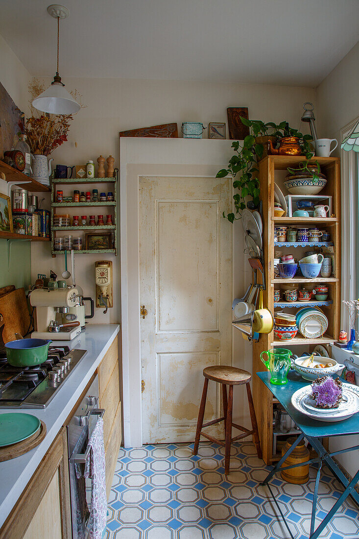 Landhausküche mit offenen Holzregalen, gemustertem Fliesenboden und Pflanze