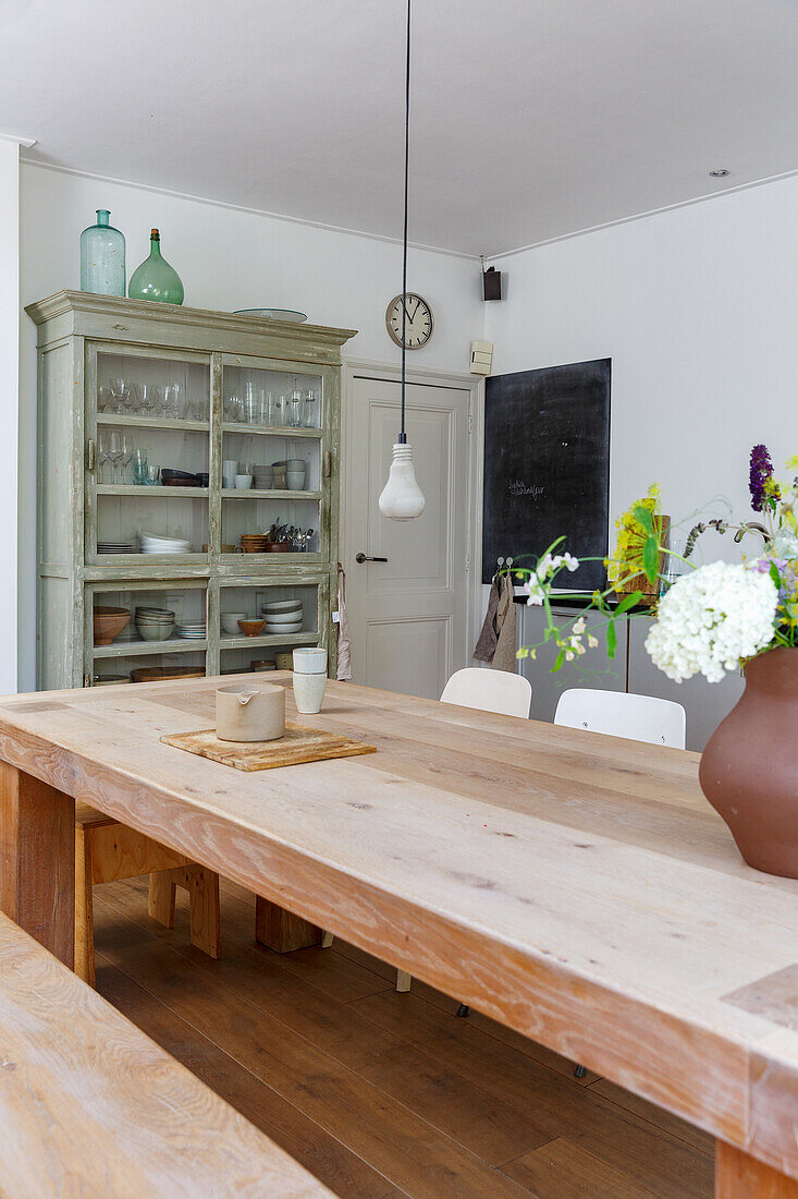 Wooden table with flower vase, display cabinet and chalkboard