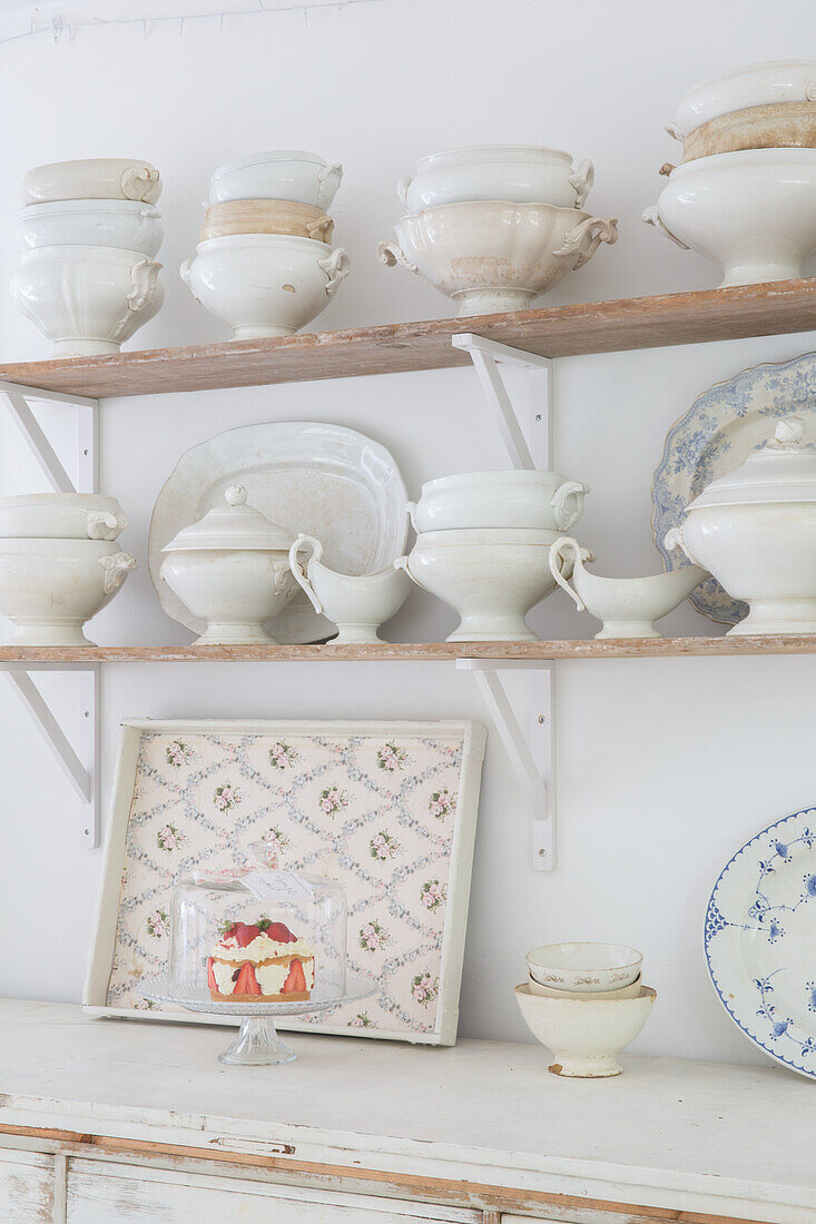 Vintage ceramic crockery on rustic wooden shelves in the kitchen