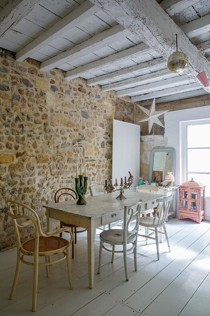 Dining room with rustic stone wall, light-coloured furniture and floorboards