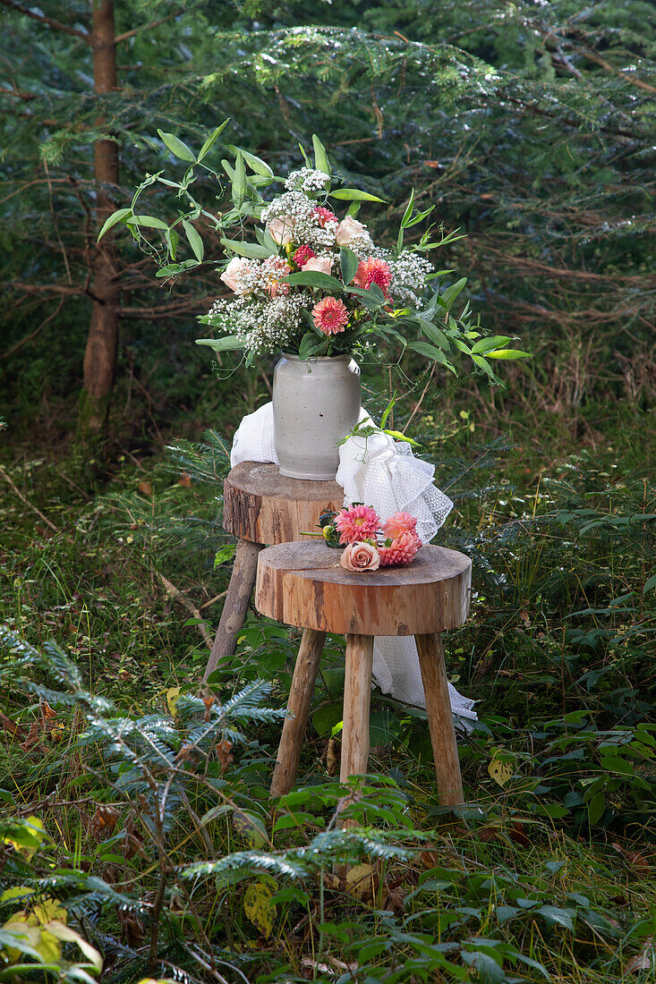 Blumenstrauß aus Sommerröschen (Cosmos) und Schleierkraut (Gypsophila) auf Holzschemel im Garten